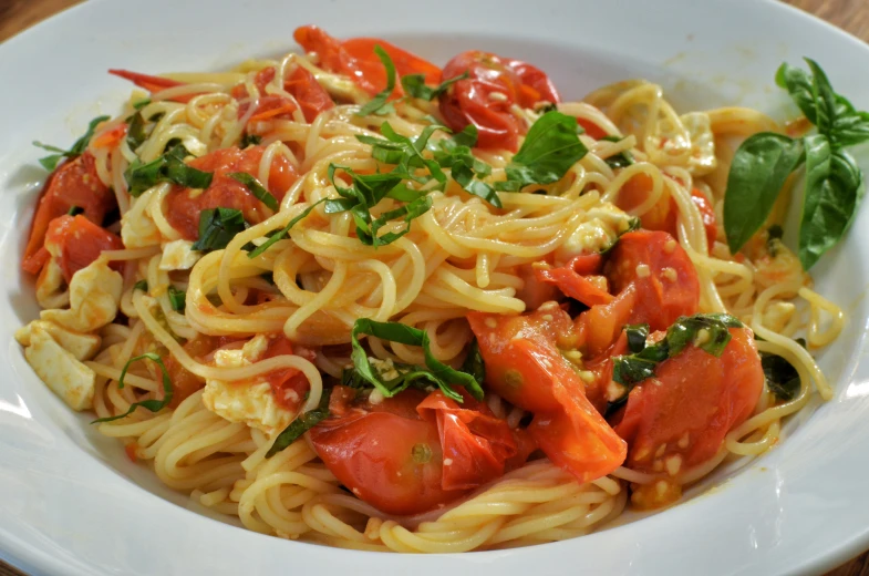 a pasta dish with tomatoes, spinach, and basil