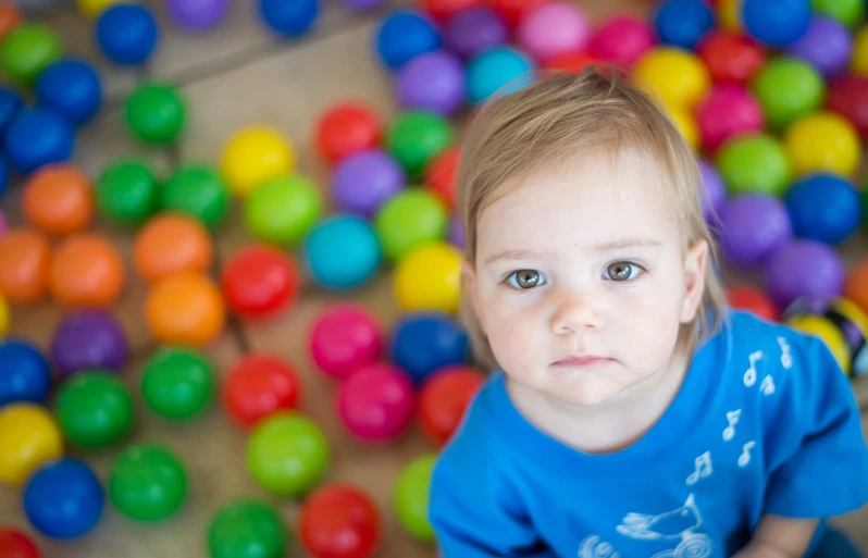 a small child stands amongst many colored balls