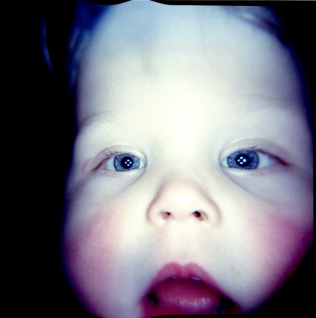 a baby stares intently into the camera lens