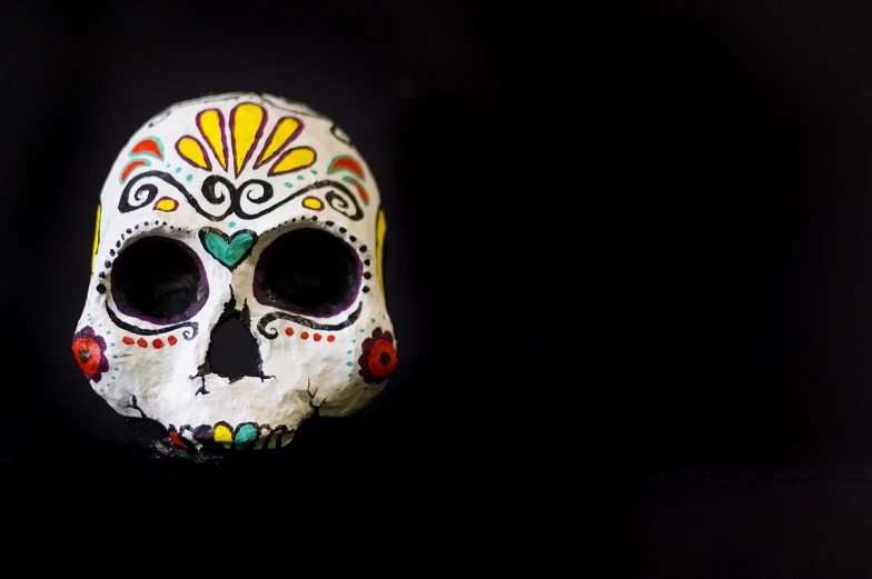 a colorfully painted sugar skull sitting in the dark