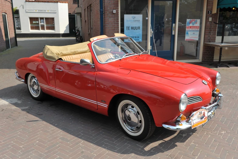 red classic car parked on brick road near buildings