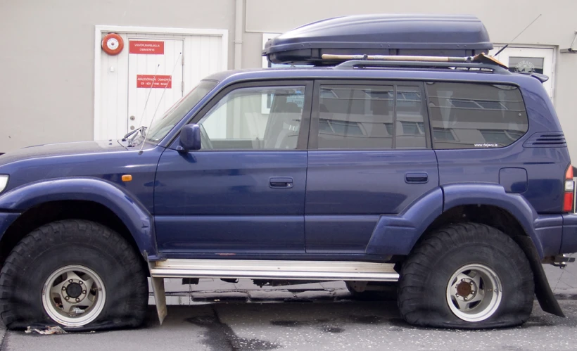 an suv with three wheels parked next to a building