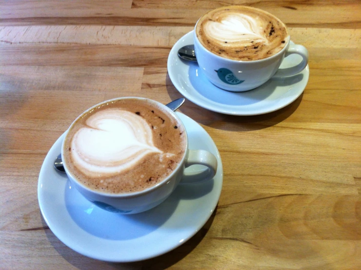 there are two cups of coffee sitting on a saucer