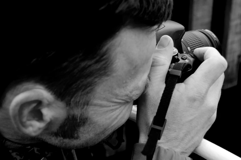 black and white pograph of person holding camera to his nose