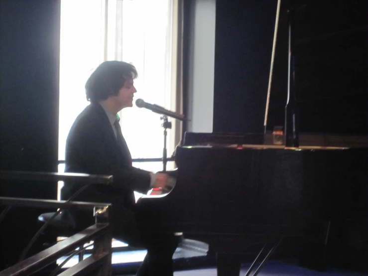 a man sitting at a piano in front of a microphone
