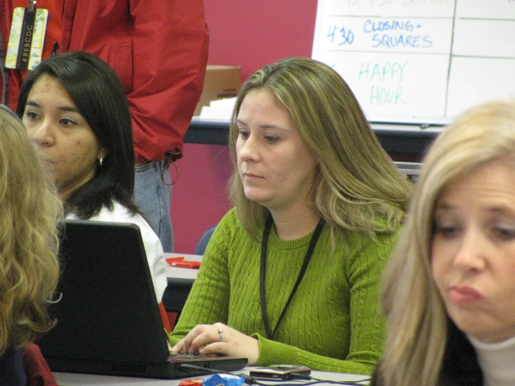 a group of people sitting at tables with laptops