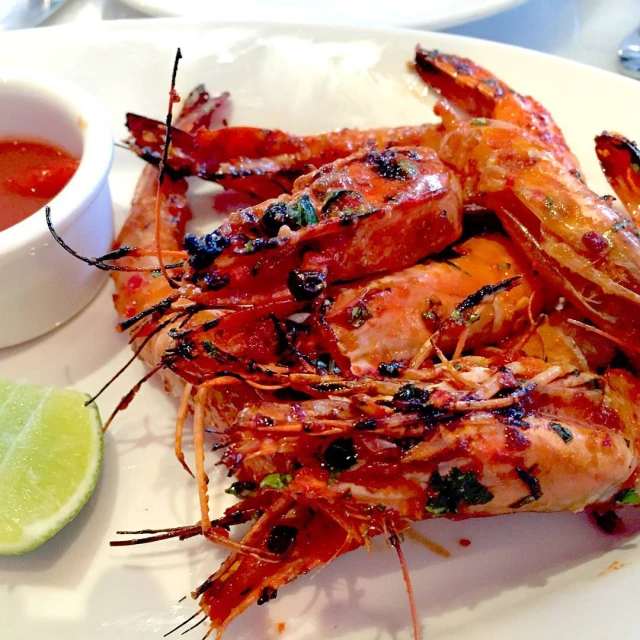 a plate topped with shrimp next to a bowl of dipping sauce