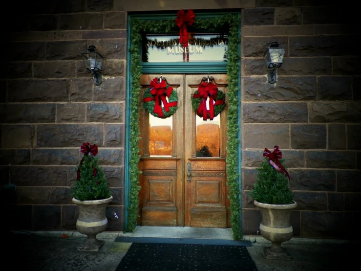 two pots with christmas decorations and wreaths on the front door