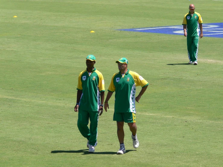 three men standing on a lush green field