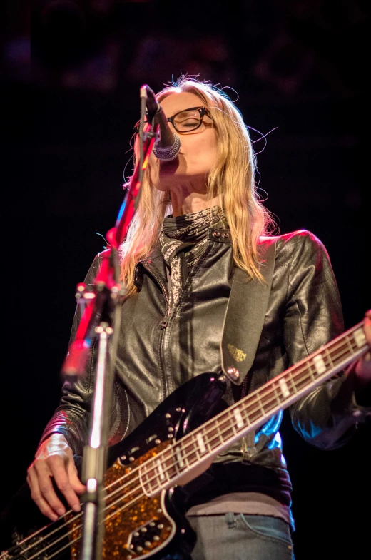 a woman with glasses on playing a guitar