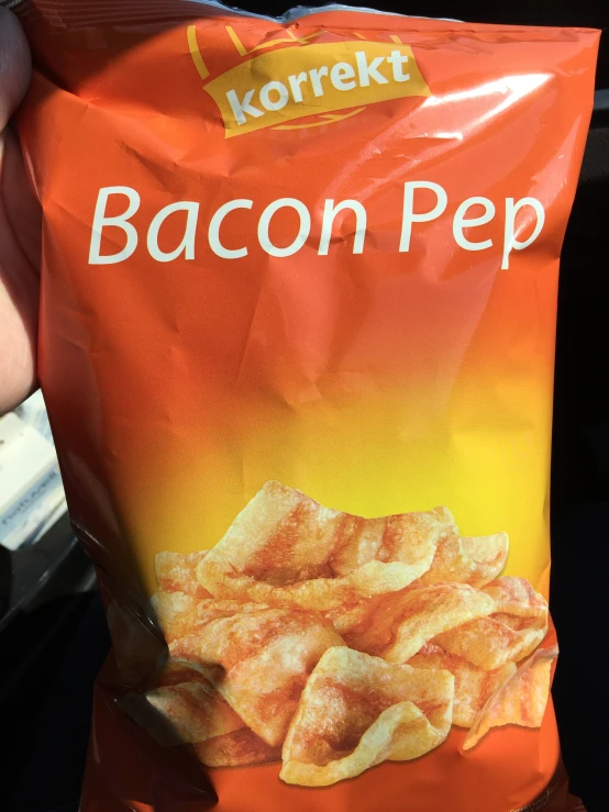 a person is holding a bag of bacon chips