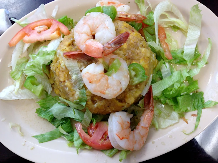 a plate of food that includes shrimp, lettuce, and tomatoes