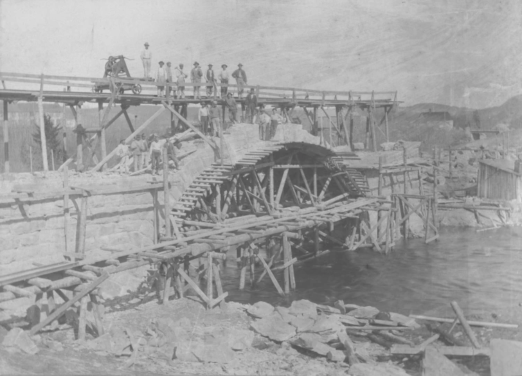 men are standing on top of the old bridge over the water