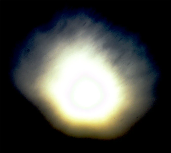 a very dark sky with a white and yellow circular in the center