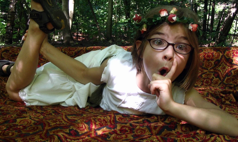 a young woman sitting on a couch, holding her finger near her mouth