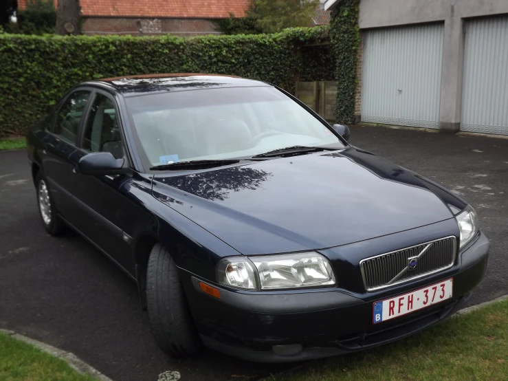 a black car is parked next to some hedges