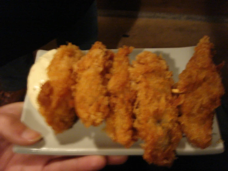 the person is holding a white plate with cooked fish