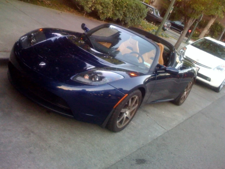 a blue sports car is parked beside a white convertible car