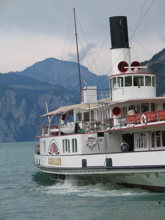 a steamboat boat with many chairs is moving on the water