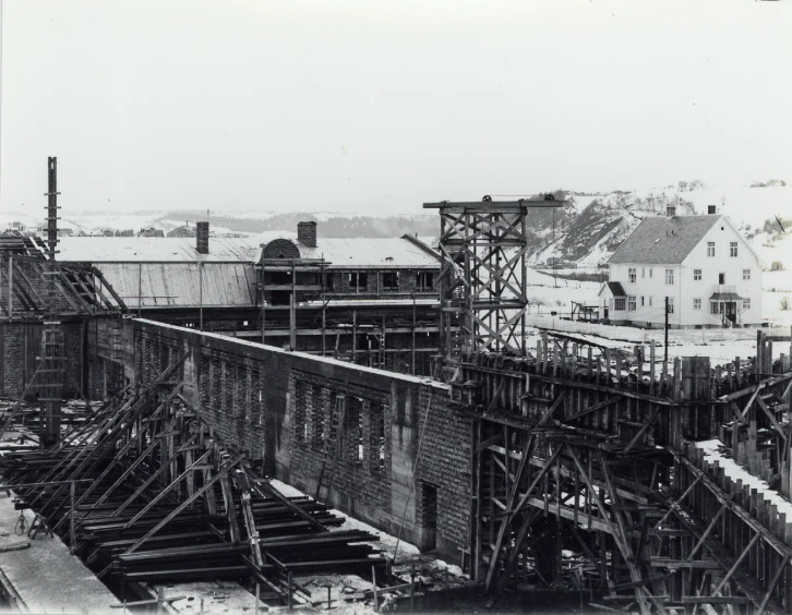 an old pograph of a factory and buildings with the train track in foreground