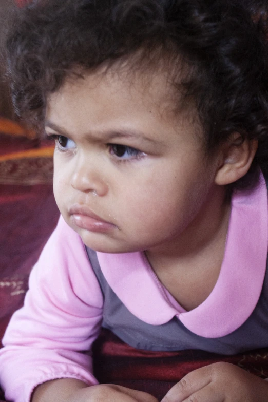 a young child in a pink shirt with an alert look on her face