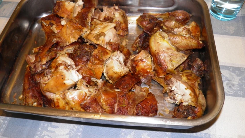 a metal tray full of cooked chicken on a table