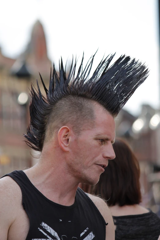 a man with long black spiked hair stands near another man with spikes on his head