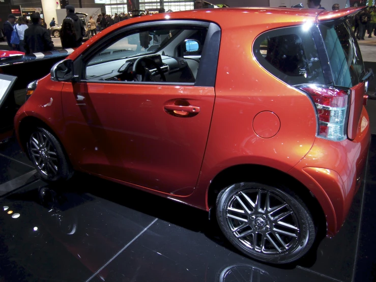 a small red smart car on display at a show