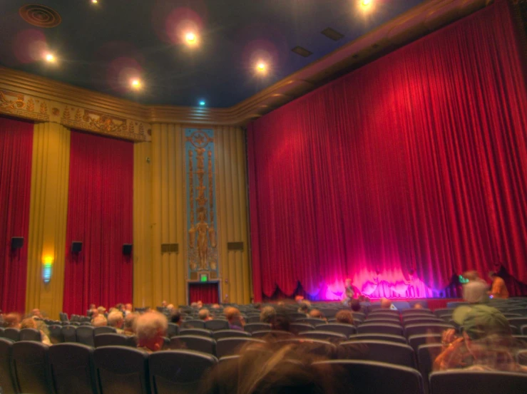 a large auditorium full of people with red curtains