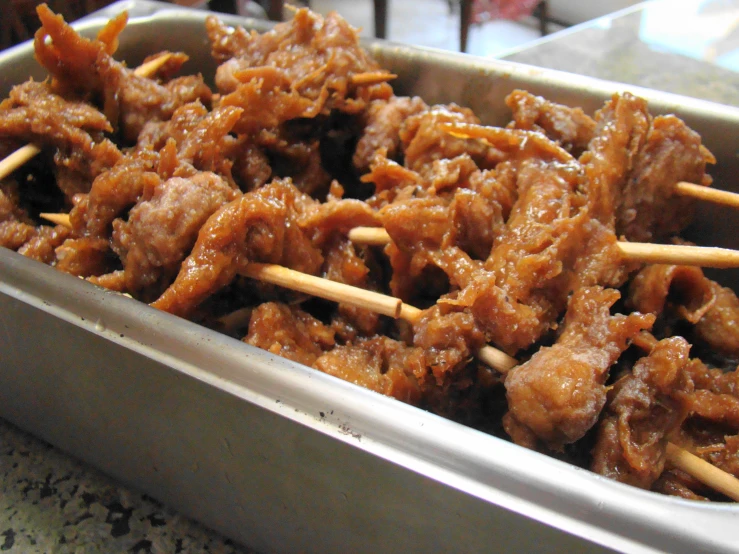 a metal tray filled with meat and sticks