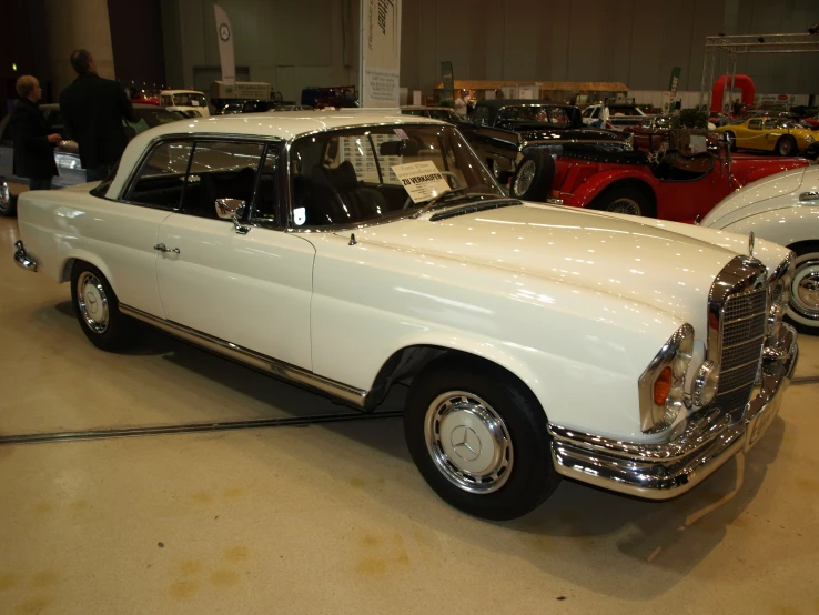 an old fashioned white car parked on a lot