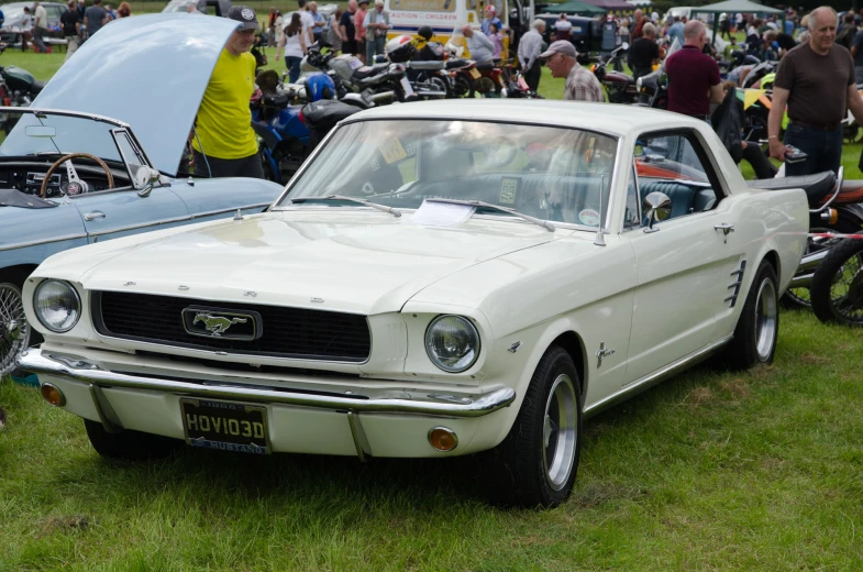 an old classic car parked in the grass with other antique cars