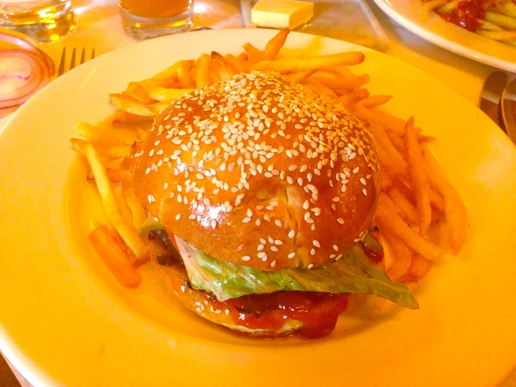 the hamburger and fries are on a yellow plate