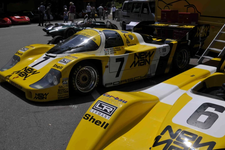 yellow race cars lined up with people looking on