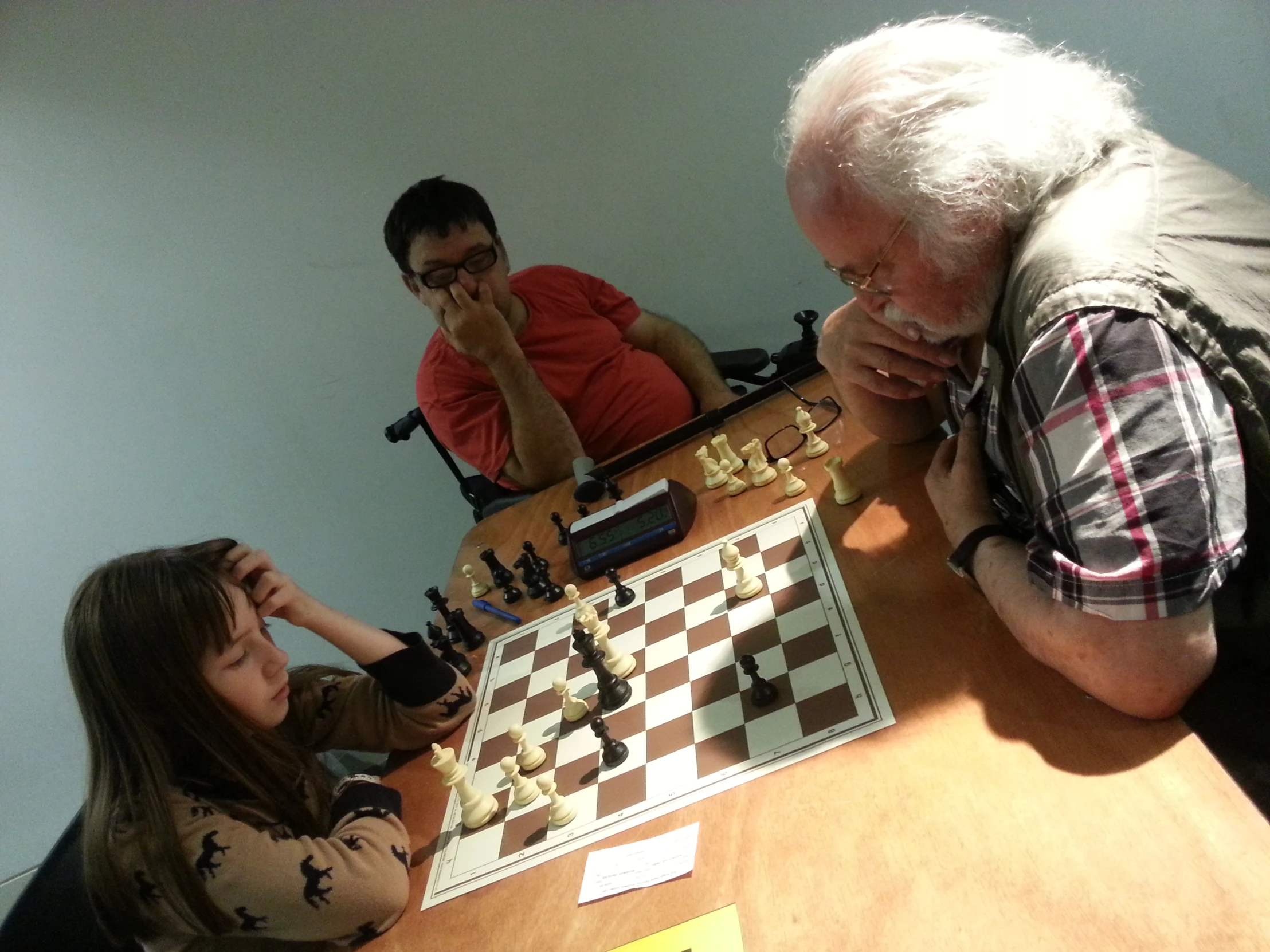 people sit around a table with chess