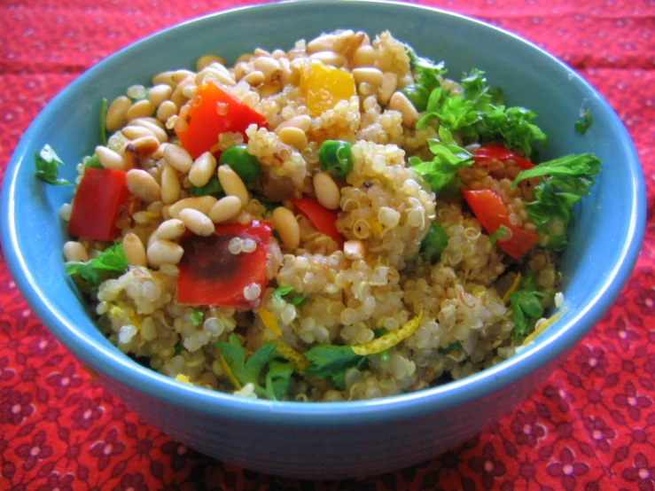 a bowl filled with grains and vegetables next to a red cloth