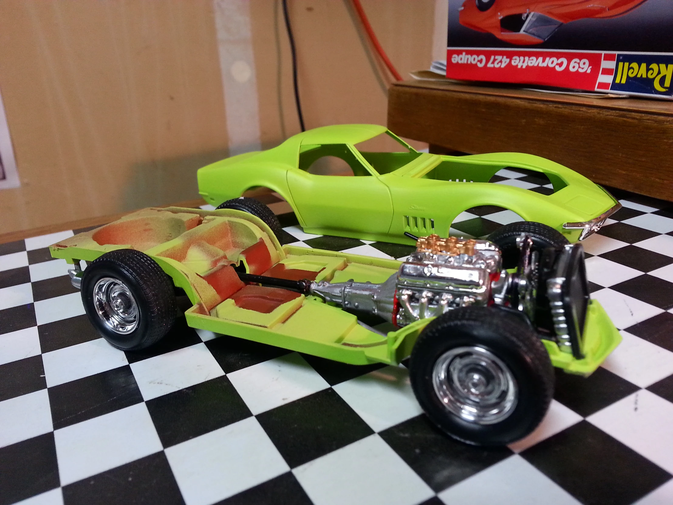 a green toy car sits on top of a black and white checkered counter