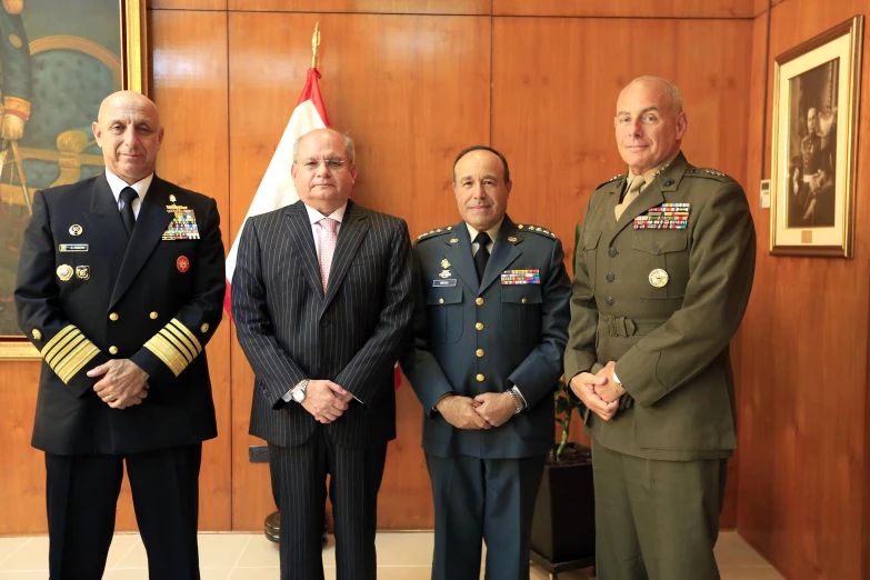 four military men posing for a po next to a flag