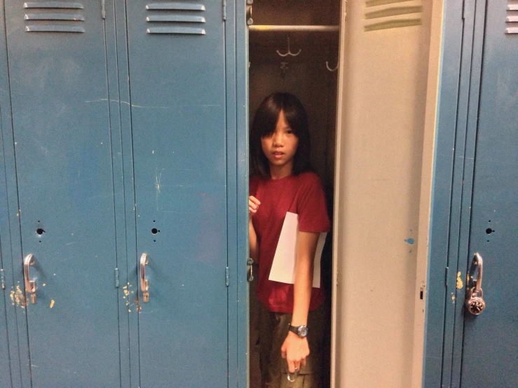 a girl standing next to some lockers in a room