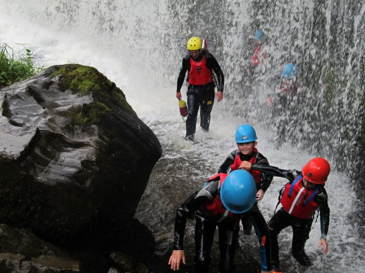 men in lifejackets standing on a rock with a waterfall behind them