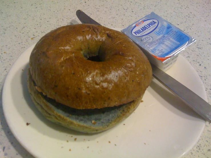a donut that has been covered in icing sits on a plate next to a knife