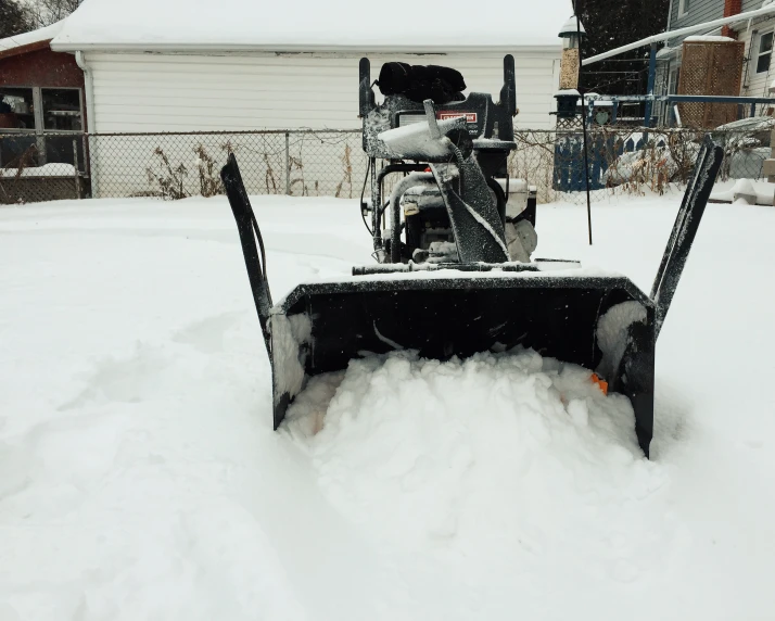 a snow - plow clearing the front yard of a house