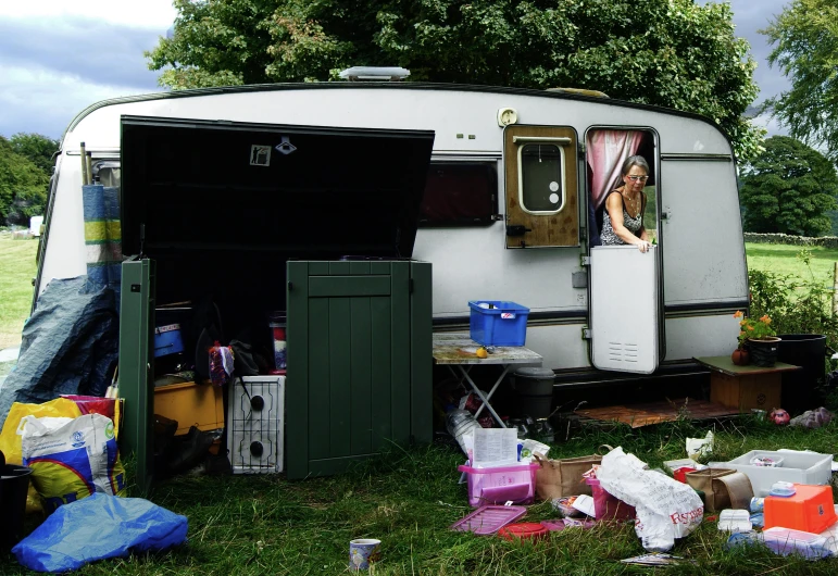 a camper trailer with doors open near many items