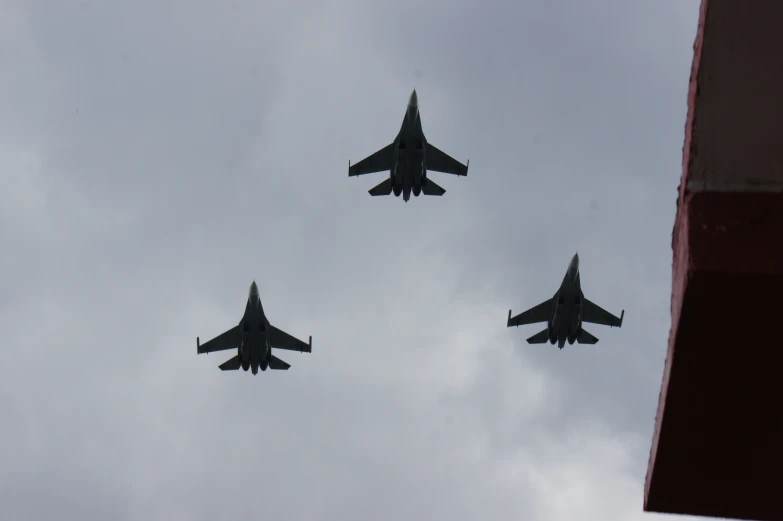 four military jets are flying in formation on cloudy skies