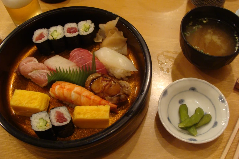 a wooden table topped with a bowl filled with sushi