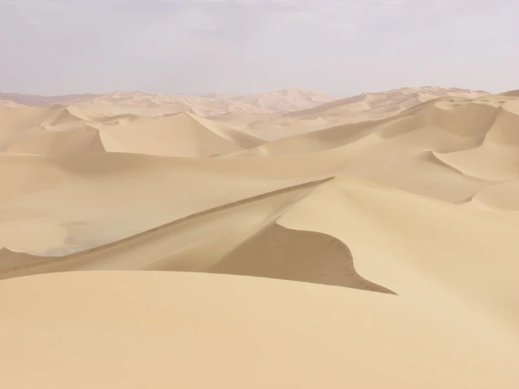 sand dunes with mountains and clouds in the background