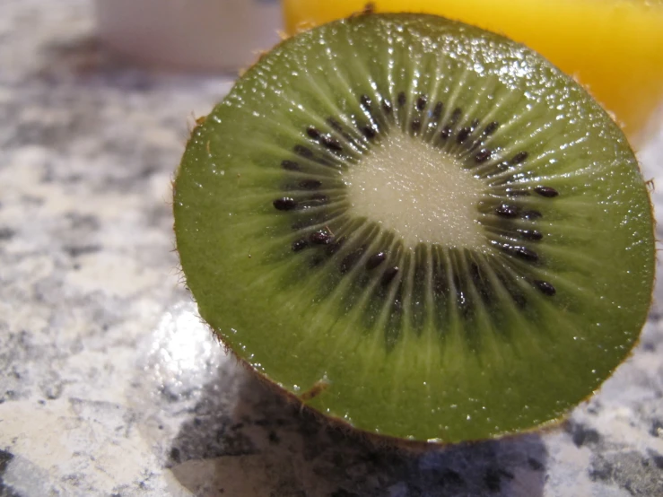 a half kiwi fruit sliced into slices on top of a granite table