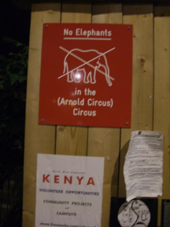 some signs hanging on a fence that say no elephants in the aerial circus circus