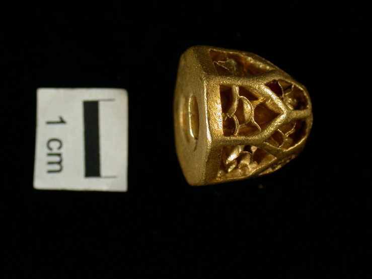 the front side of an antique gold ring with filigree detail on it and two tags