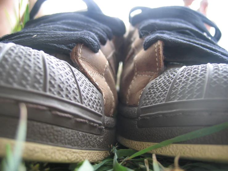 two pairs of brown shoes laying in the grass